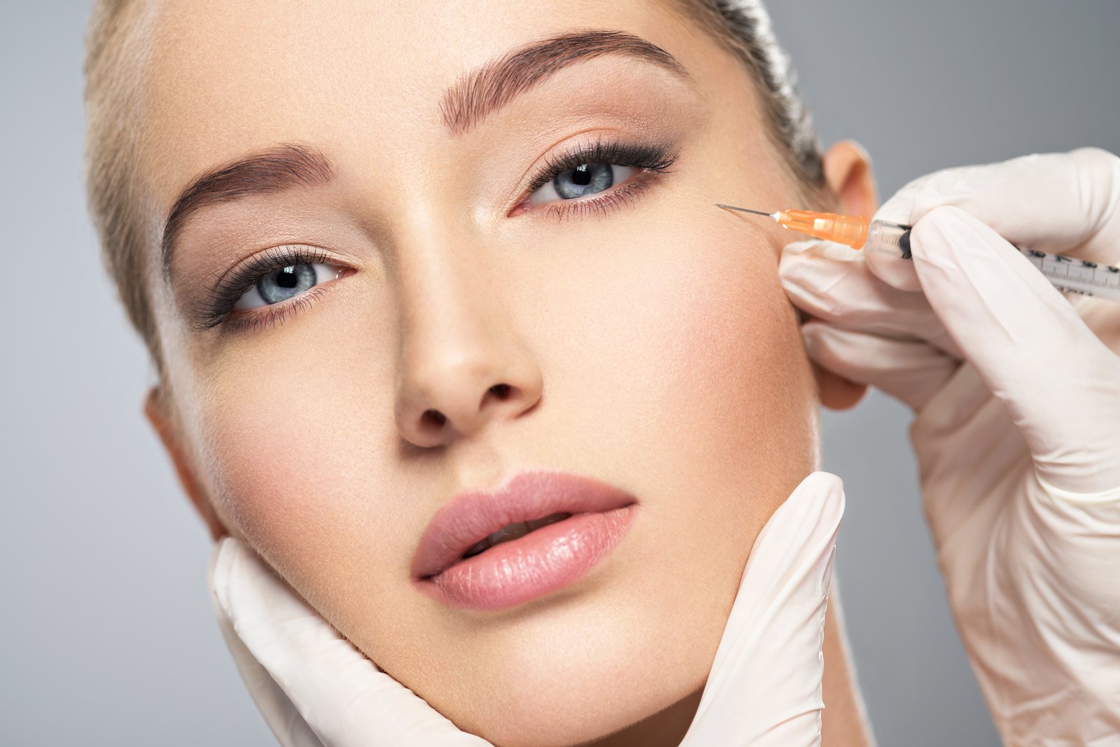 Woman getting cosmetic injection of botox in cheek, closeup. Woman in beauty salon. plastic surgery clinic.
